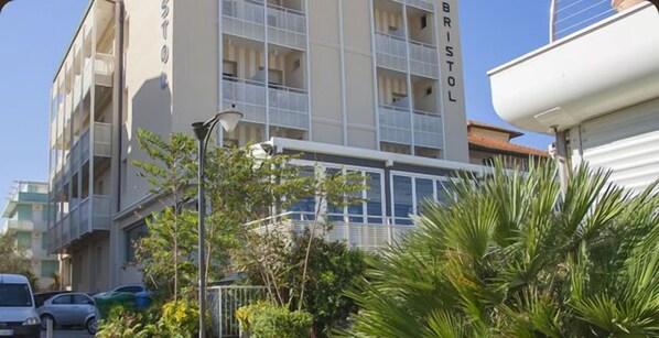 A multi-story building with balconies, a street lamp, and parked cars.