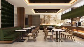 A modern restaurant with green seating, white tables, and a bar area.