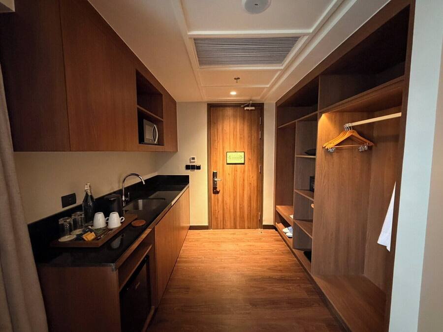 A compact kitchen with a microwave, sink, and wooden cabinets.