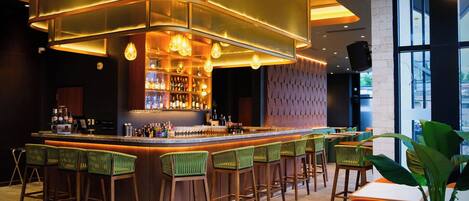 A bar area with a curved counter, multiple stools, and a well-lit interior.