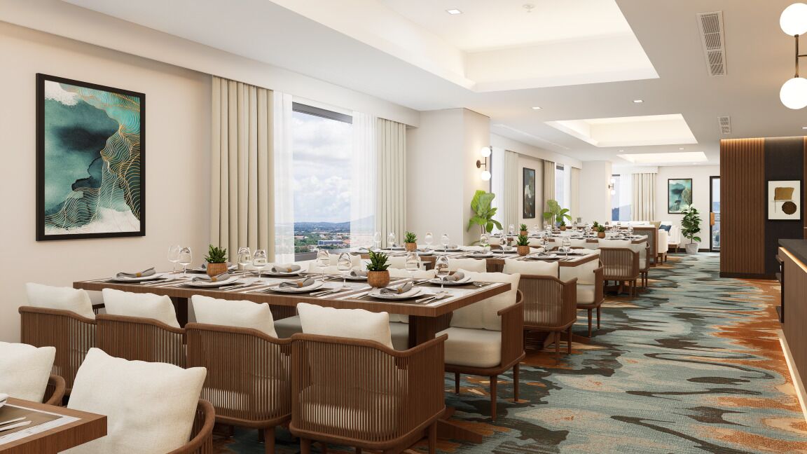 A modern hotel dining area with long tables, wicker chairs, and a view of the city.