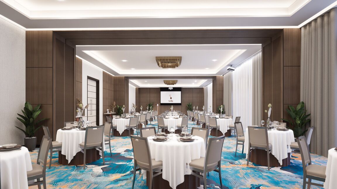 A spacious conference room with multiple tables and chairs, a large screen at the front, and a patterned carpet.