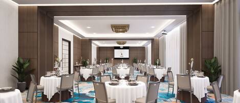 A spacious conference room with multiple tables and chairs, a large screen at the front, and a patterned carpet.