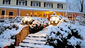 A hotel with a covered front porch, steps leading up to the entrance, and snow-covered bushes. - The Orchard Inn (Saluda)