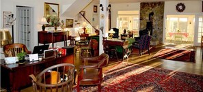 A spacious living room with a wooden floor, a large rug, and a staircase leading to another level.