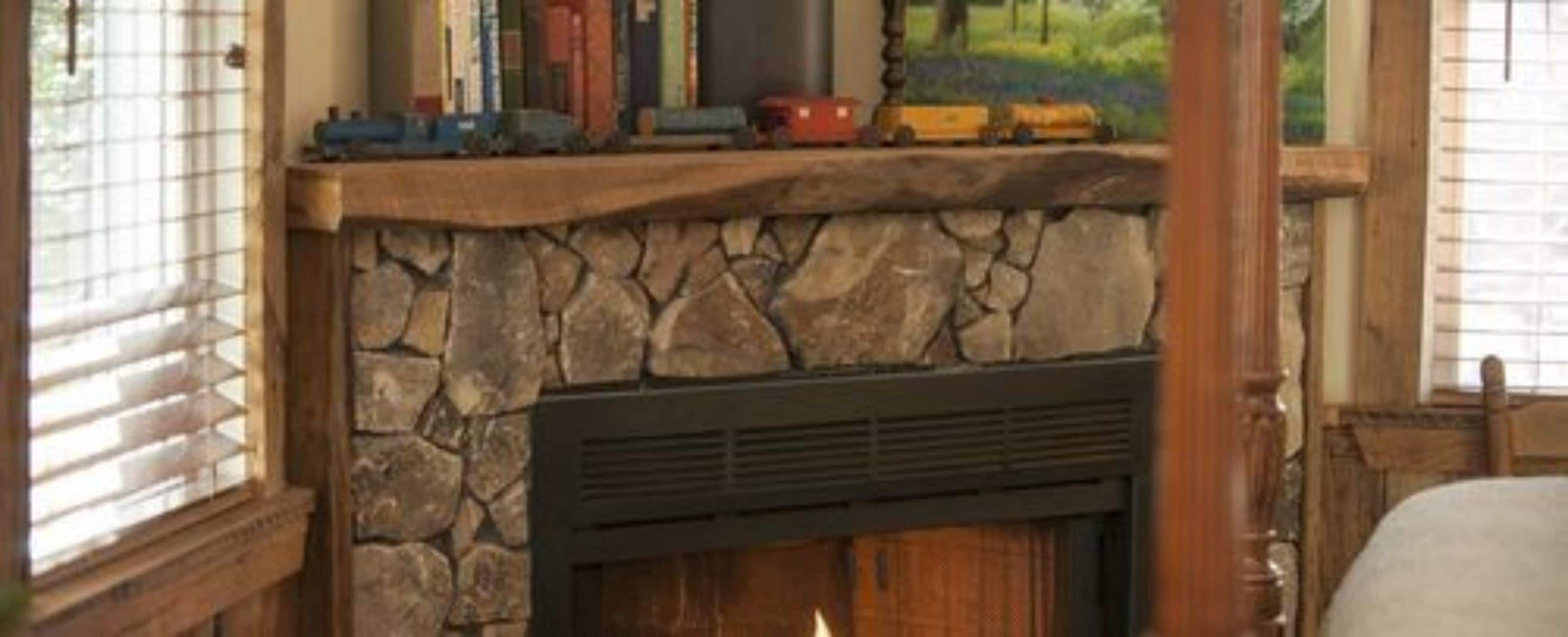Una chimenea de piedra con un respiradero negro, rodeada de libros y un tren de juguete.