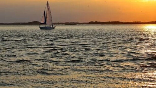Un velero sobre aguas tranquilas durante el atardecer.