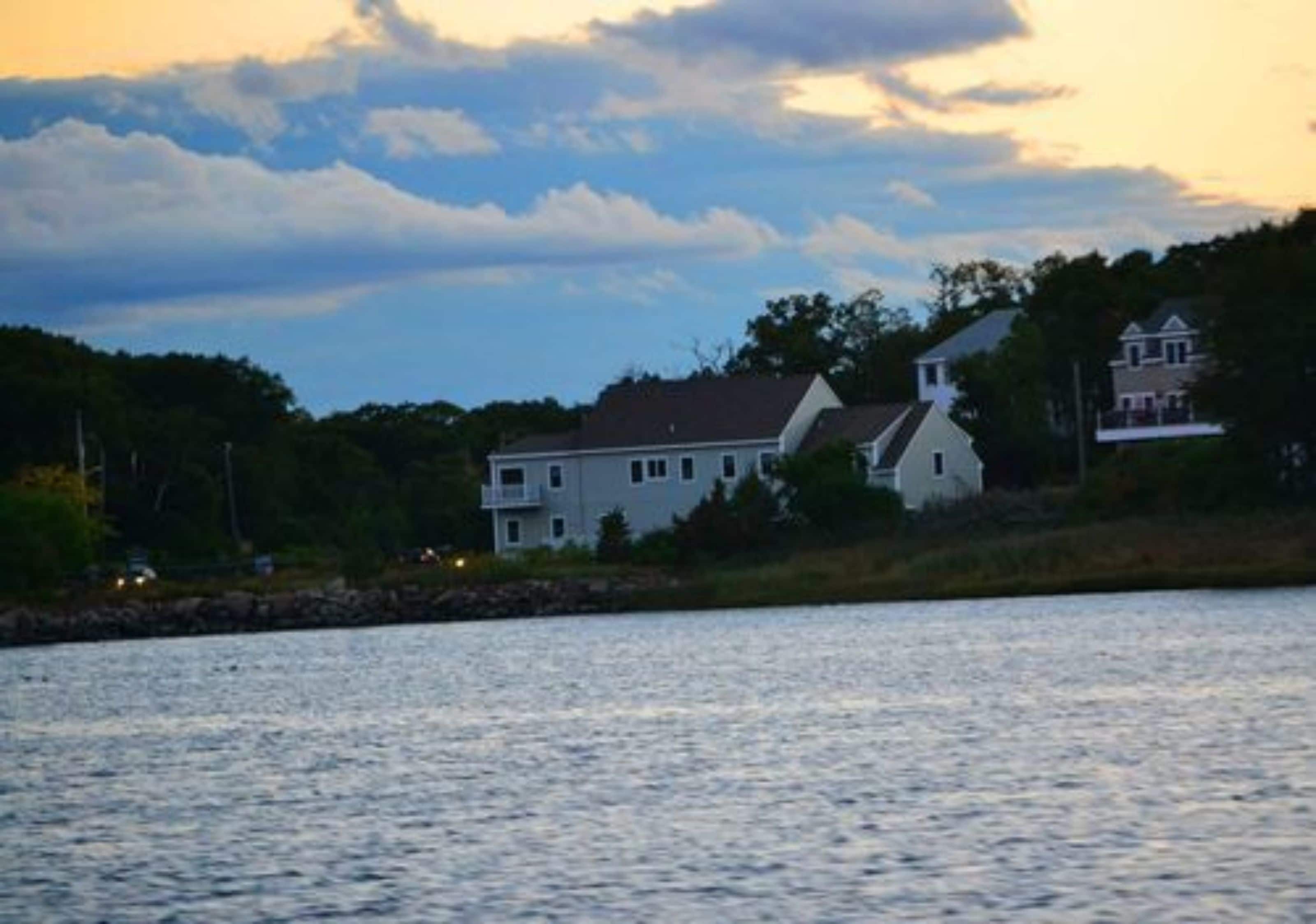 A waterfront property with a large house featuring multiple windows and a prominent chimney.