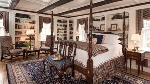 Une chambre à coucher de style traditionnel, avec un lit à baldaquin, une grande bibliothèque et un plancher en bois classique.