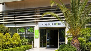 The exterior of Athinais Hotel with a modern facade, a palm tree, and well-maintained landscaping. - Athinais Hotel (Athens)