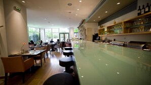 A restaurant with a long counter, bar stools, and a wine display. - Athinais Hotel (Athens)