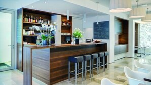 A modern bar area with a wooden counter, bar stools, and a variety of bottles and glasses. - Stern am Rathaus (Cologne)
