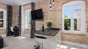 Une cuisine moderne avec un mur en briques, un téléviseur à écran plat, un coin bar avec des tabourets et de grandes fenêtres.