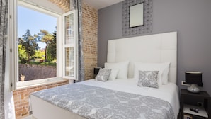 Une chambre à coucher avec un grand lit, une fenêtre avec des rideaux, un mur en briques et une tête de lit moderne.