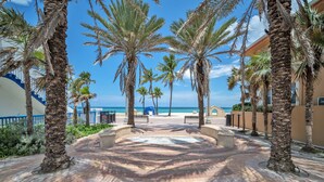A palm tree-lined pathway leading to a beach with a clear view of the ocean. - Laguna Blu Beach (Hollywood)