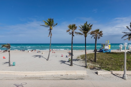 A beach with palm trees, a lifeguard tower, and a clear blue sky.