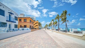 A paved walkway with palm trees, a Marriott hotel, and a beach in the background. - Laguna Blu Beach (Hollywood)