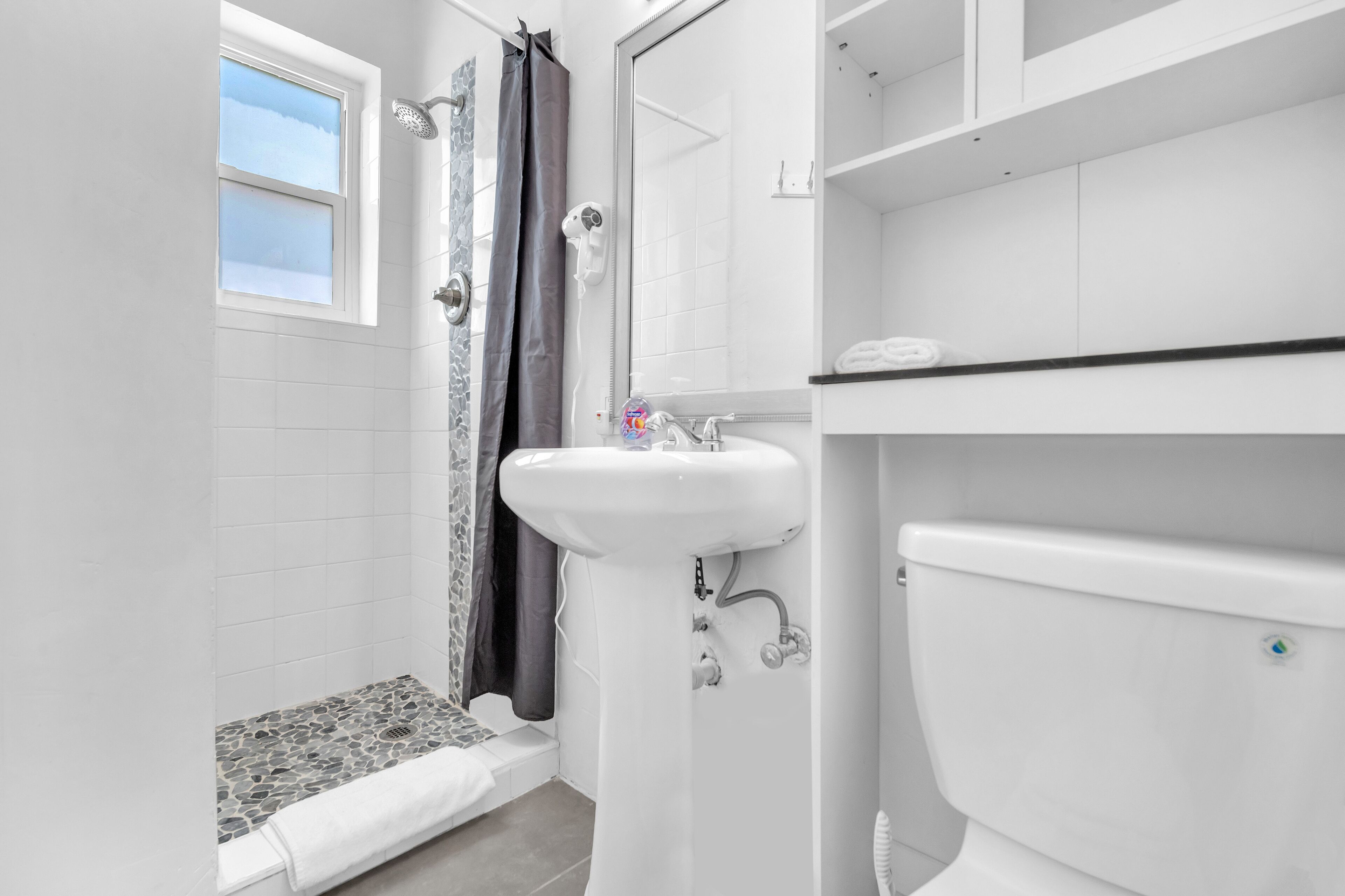A bathroom with a shower, a sink, and a toilet.