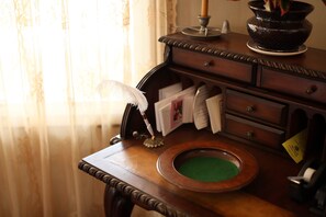 Un escritorio de madera con un tintero verde, una pluma de ave y una vela.