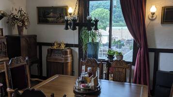 Un comedor con una mesa de madera, sillas y una araña. Se ve un ventanal con vistas a la vegetación.
