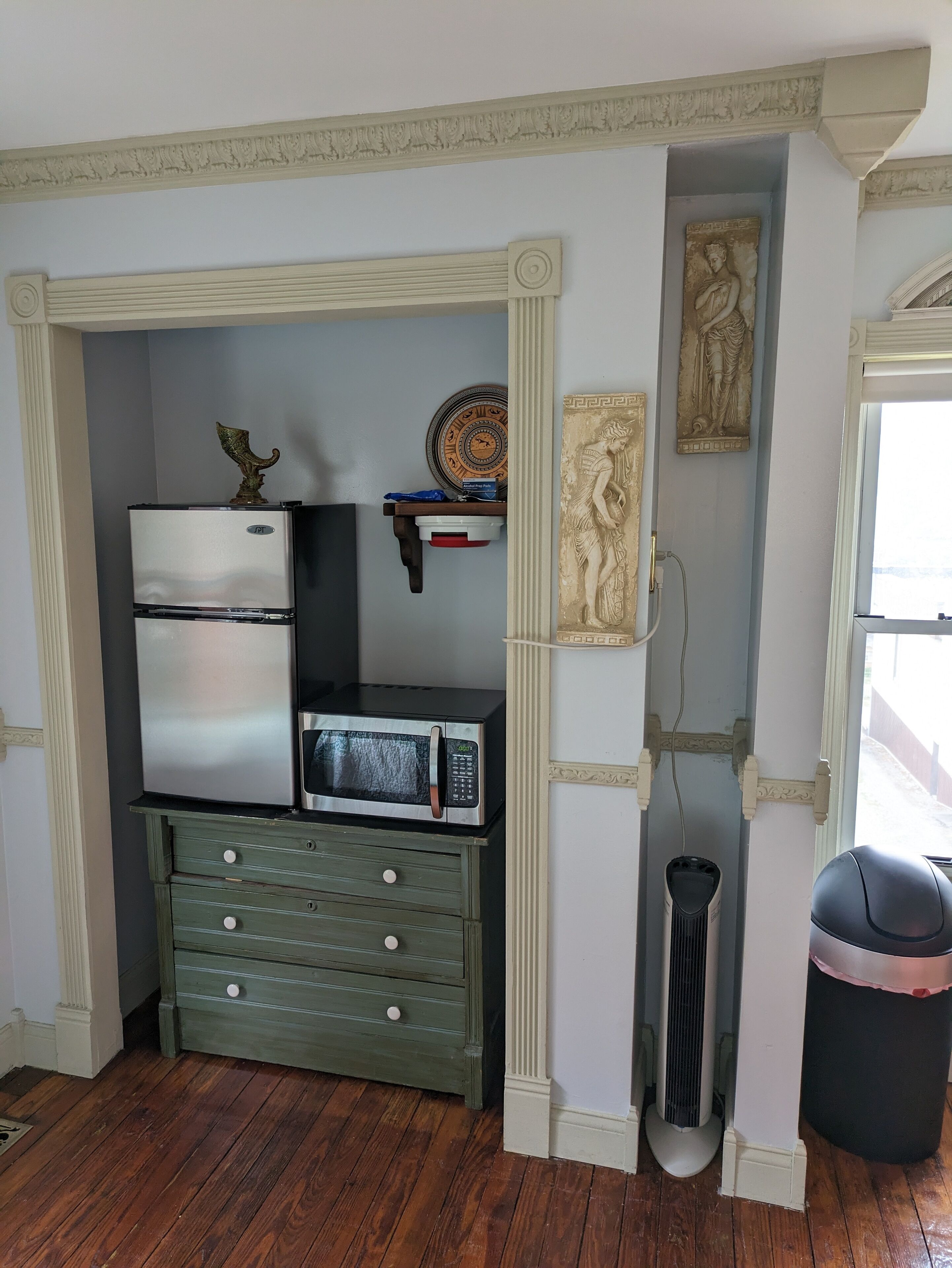 A compact kitchen with a refrigerator, microwave, and a small cabinet.