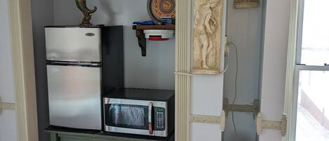 A compact kitchen with a refrigerator, microwave, and a small cabinet.