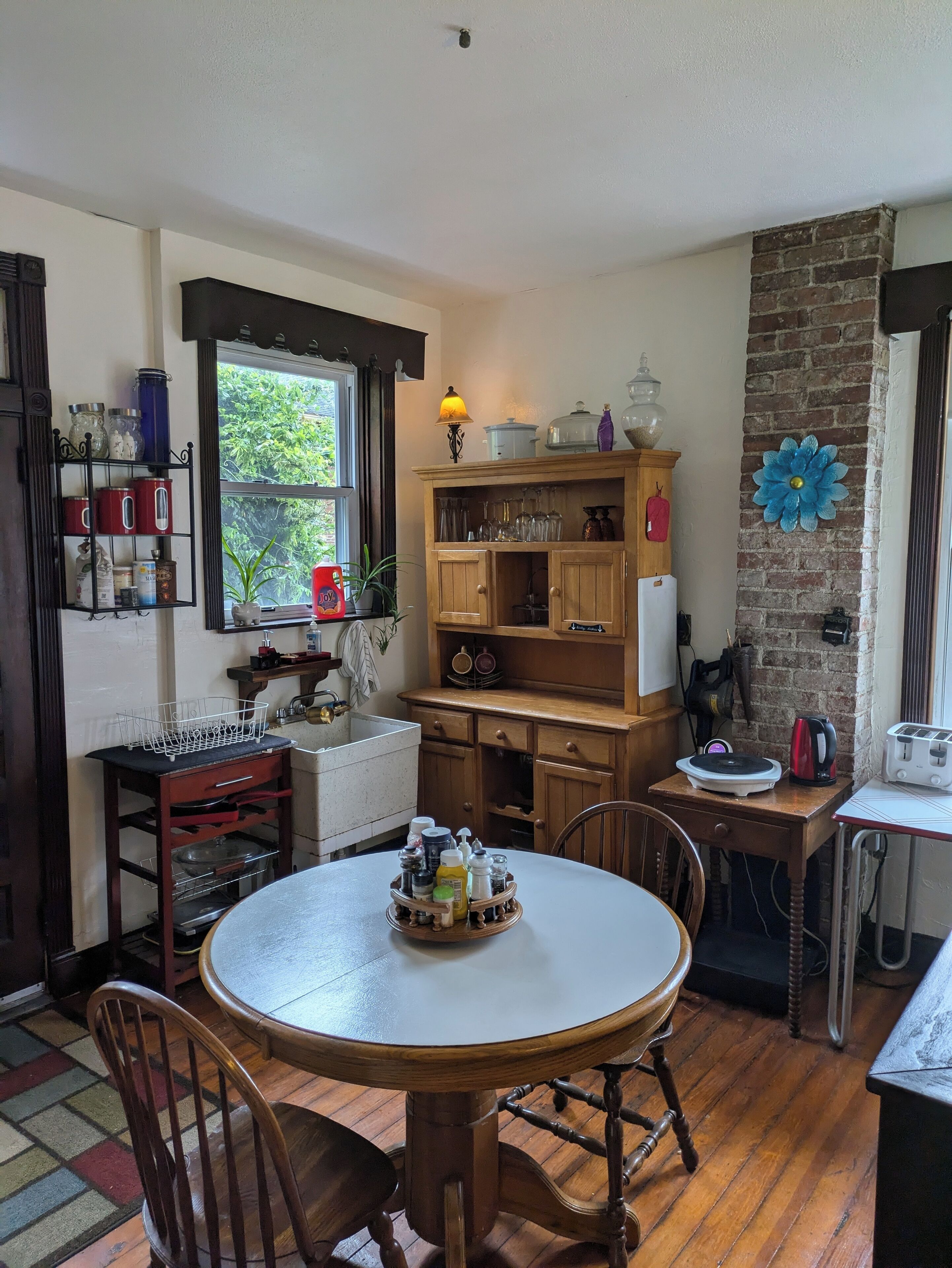 A cozy kitchen with wooden cabinets, a round dining table, and a brick accent wall.