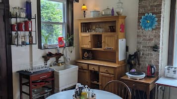 A cozy kitchen with wooden cabinets, a round dining table, and a brick accent wall.