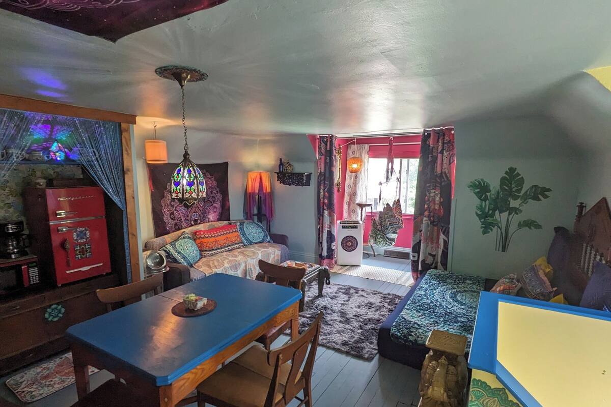 A cozy living area with a dining table, chairs, a sofa, and a decorative ceiling.