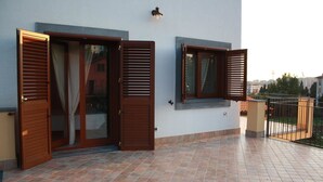 A balcony with two wooden doors and windows, a tiled floor, and a light fixture on the wall. - La Circumetnea B&B (Catania)