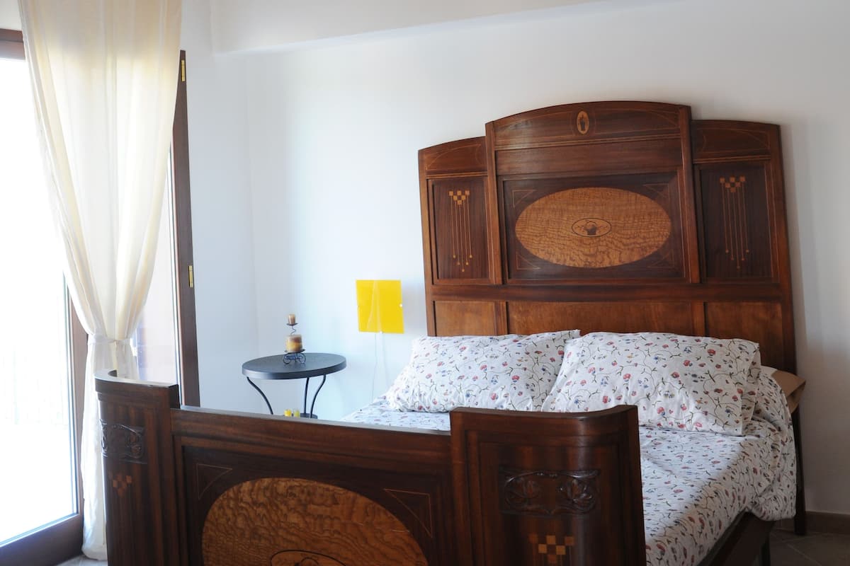 A bedroom with a wooden ceiling, a bed with a headboard, a bedside table, and a nightstand.