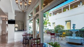 A hotel interior with a dining area, a kitchen, and a view of the outside. - Palm Beach Historic Inn (Palm Beach)