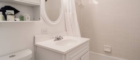 A bathroom with a white sink, mirror, and shower curtain.