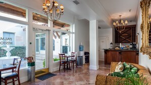 A spacious living area with a dining table and chairs, a kitchen with a bar, and a large mirror. - Palm Beach Historic Inn (Palm Beach)
