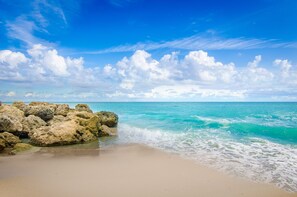 Una playa con aguas turquesas cristalinas, arena blanca y grandes rocas.