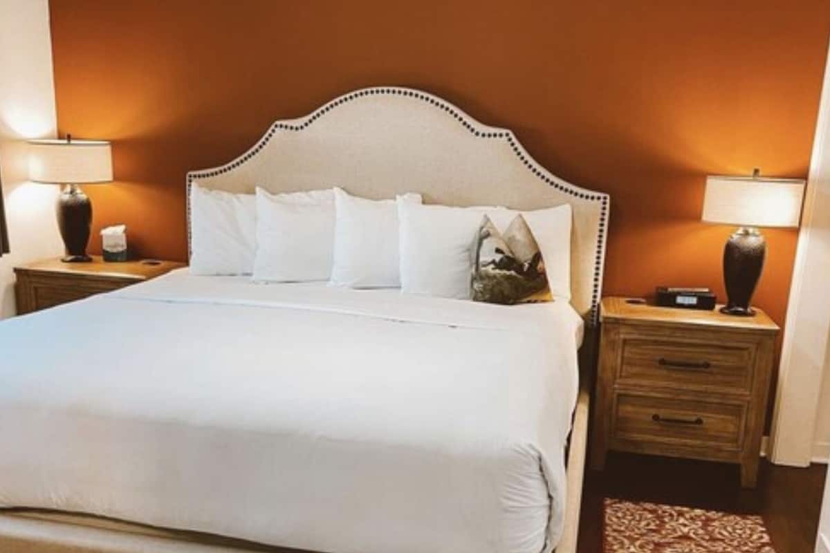A hotel room with a large bed, two bedside tables, and a nightstand with a lamp.