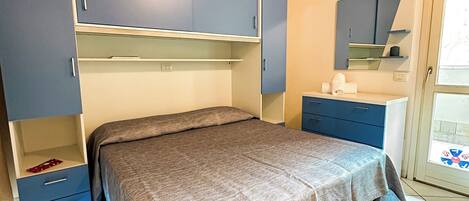 A bedroom with a bed, a wardrobe, a dresser, and a mirror.