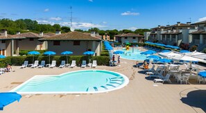 Una piscina al aire libre, sombrillas, sillones reclinables de piscina