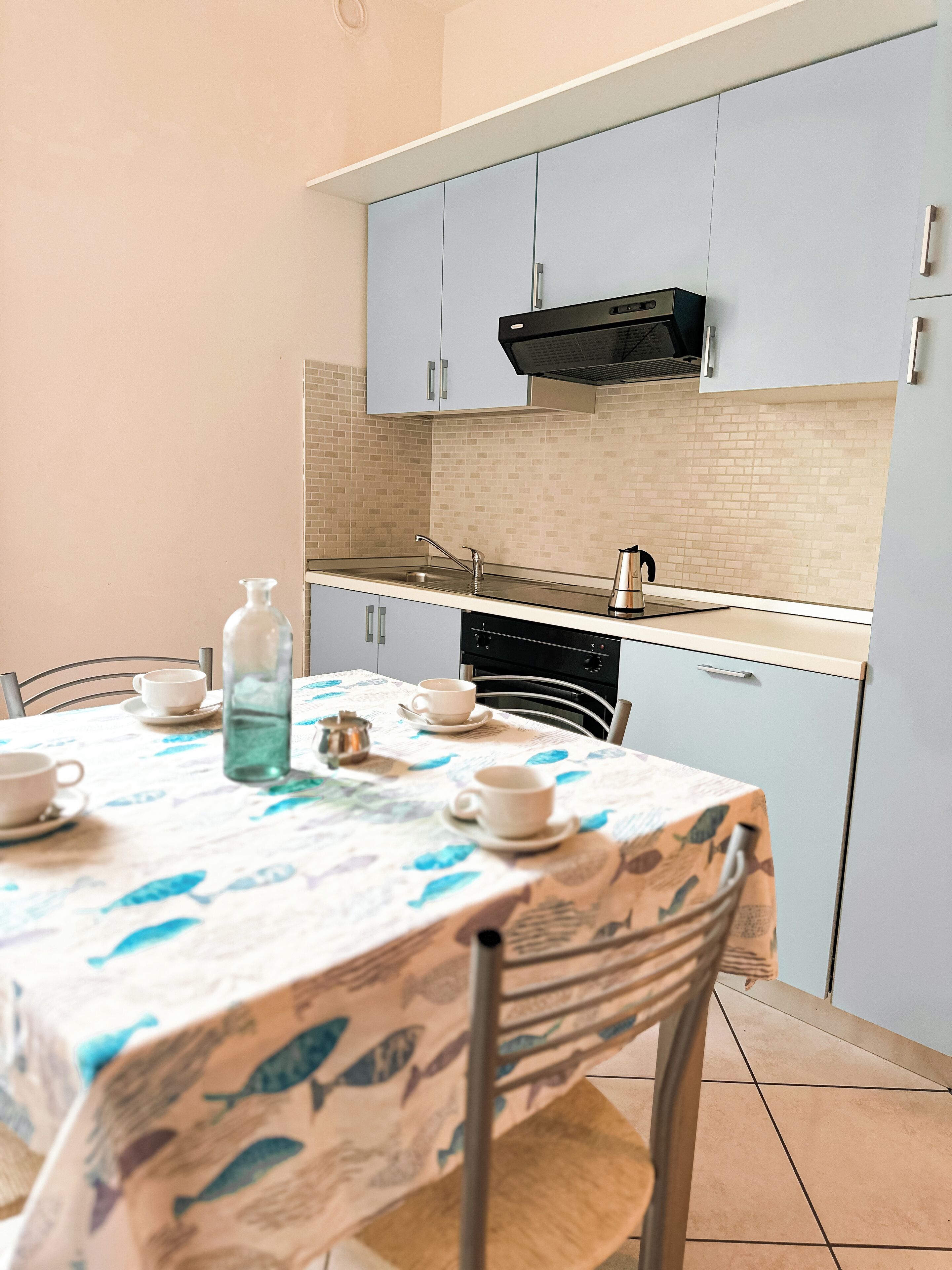 Een kleine keuken met een eettafel, stoelen en een betegelde spatwand.