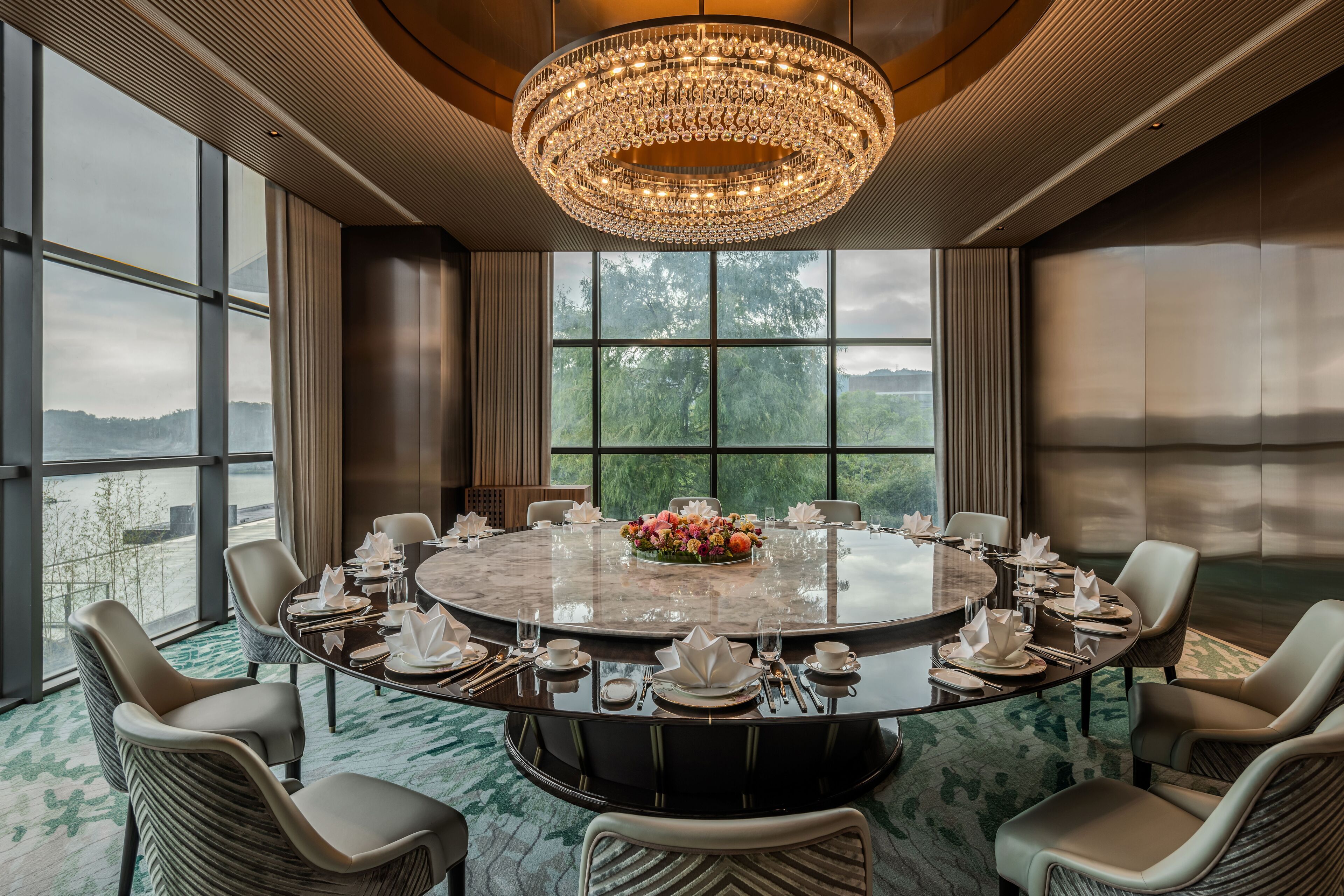 A conference room with a round table, chairs, and a chandelier.