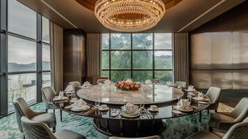 A conference room with a round table, chairs, and a chandelier.