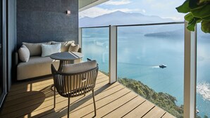 A balcony with a sofa, a round table, and chairs, overlooking a calm sea and distant mountains. - GRAND HILAI SUN MOON LAKE (Yuchi)