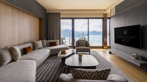 A modern living room with a large sofa, a coffee table, and a TV. The room has a view of the sea and mountains. - GRAND HILAI SUN MOON LAKE (Yuchi)