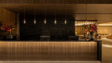 A reception area with a wooden reception desk, a stone wall, and a seating area with a sofa and chairs.