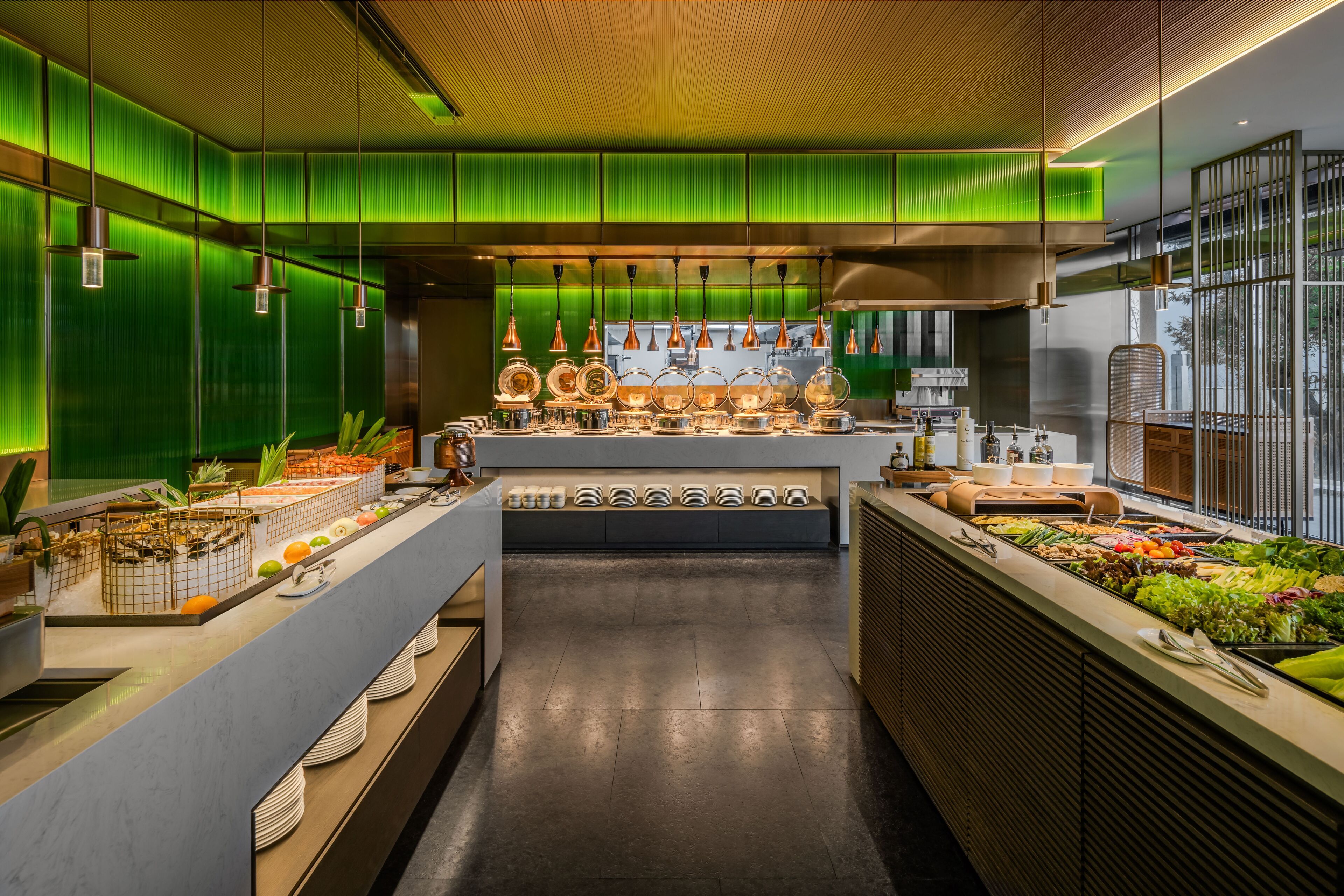 A modern kitchen with a central island, green walls, and pendant lighting.
