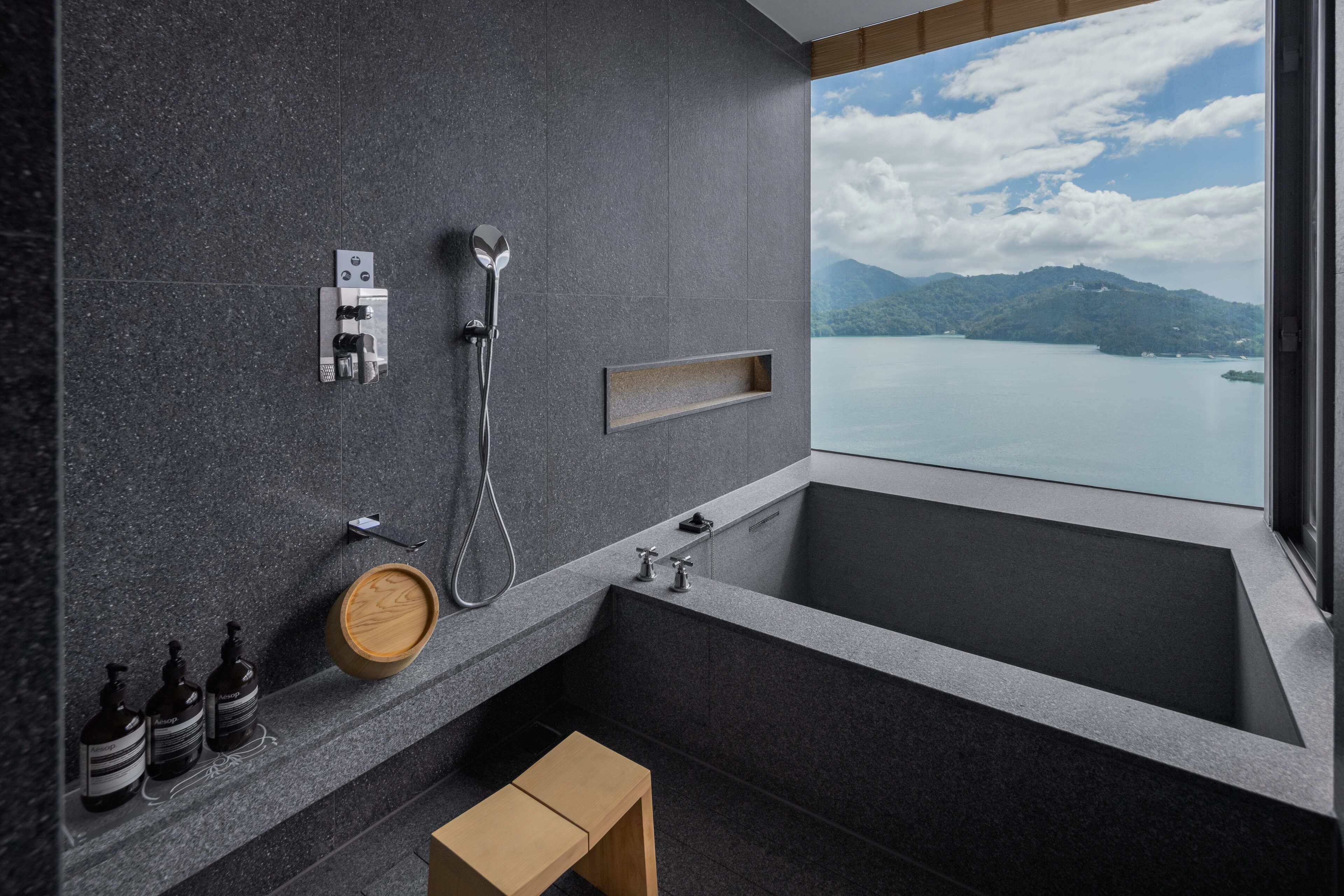Une salle de bain moderne dotée d’une grande baignoire, d’une douche et offrant une vue sur un lac.
