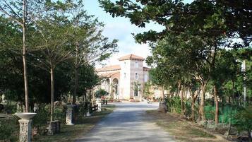 A pathway leading to a building with a tiled roof and arched windows.