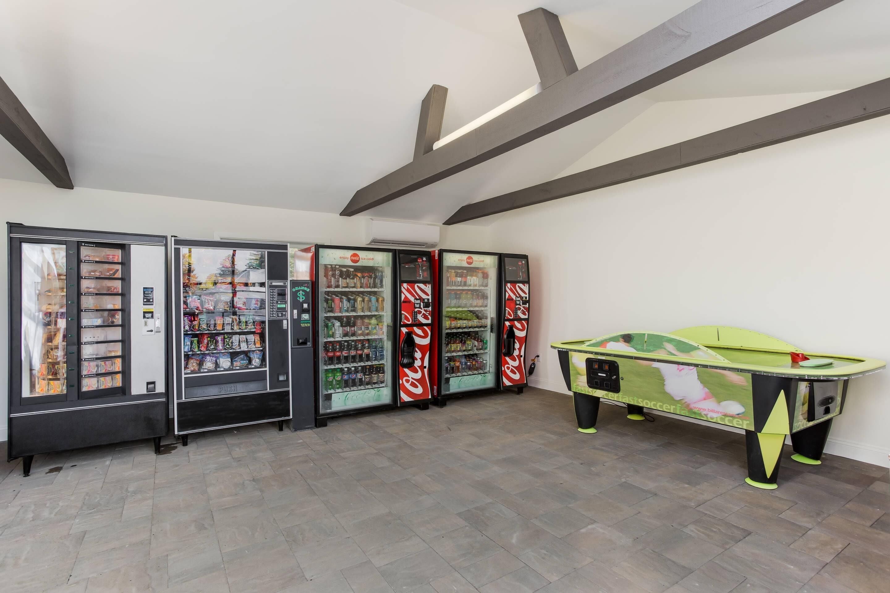 A room with vending machines, a pool table, and a tiled floor.