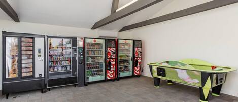 A room with vending machines, a pool table, and a tiled floor.
