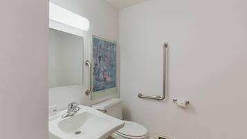 A bathroom with a white sink, toilet, and handrails.
